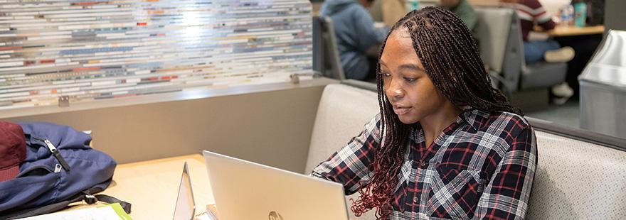 An SPU student works on their laptop in the commuter lounge on campus